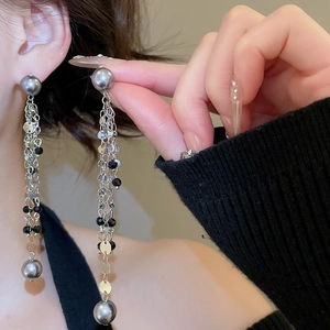 Close-up of elegant long tassel earrings with silver chains and grey pearls on model