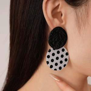 Macro detail of model wearing vintage acrylic black and white polka dot round stud earrings