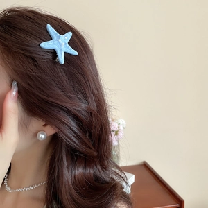 Detail of light blue starfish hair clip with bionic texture on wavy brown hair