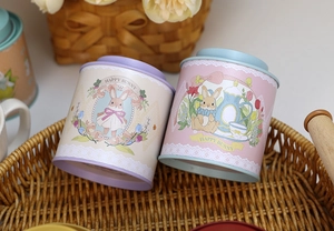 Detailed top view of decorative tin cans with pastel lids on a woven tray for gift storage