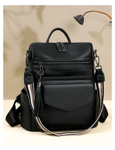 Detail of vintage PU leather backpack with tricolor woven strap and decorative side tassel