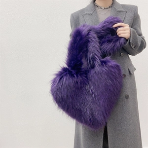 Close-up of vibrant purple faux fur heart-shaped handbag with long hair texture