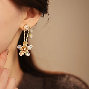 Close-up of a model wearing gold flower drop earrings with pearls and colorful crystals
