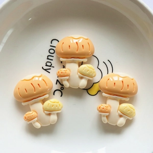 Close-up of orange mushroom resin charms for DIY crafts inside a white ceramic bowl