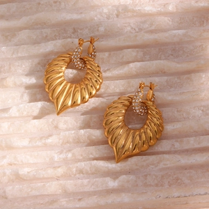 Macro detail of gold striped fan-shaped earrings with sparkling zircon stones