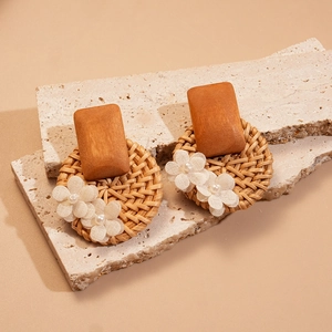 Detail of bohemian rattan earrings with wooden squares, fabric flowers and pearls