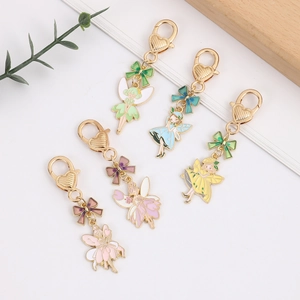Colorful enamel fairy keychains with golden heart clasps and matching bows on white background