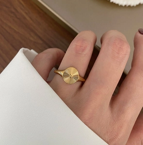 Détail de la bague en plaqué or 18 carats avec texture soleil rayonnante sur la main