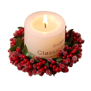 Lighted white pillar candle with red berry and green leaf wreath for Christmas table decor