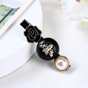 Detail einer Vintage-Blumen-Haarklammer mit Goldbienen-Emblem und elegantem Perleneinsatz