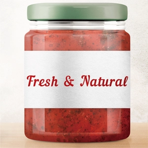 Close-up of fresh sauce in glass jar with green metal lid and elegant white texture label