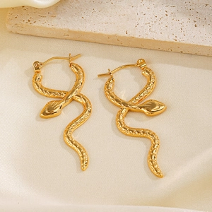 Vintage golden snake earrings with textured scales displayed on natural stone
