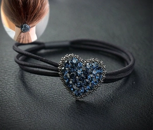 Détail d'un élastique à cheveux noir orné d'un cœur étincelant en strass bleu foncé
