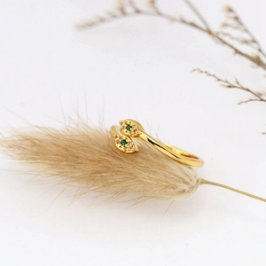 Vintage gold open ring with snake eye design and green crystals on hay background