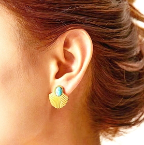 Elegant gold-tone fan-shaped fan earrings with turquoise stone worn by a model in a side view