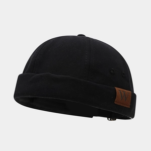 Gros plan détaillé d'un bonnet docker noir en toile avec étiquette en cuir à lettre W