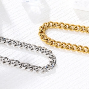 Classic Cuban link chains in gold and silver finish on a minimalist textured surface