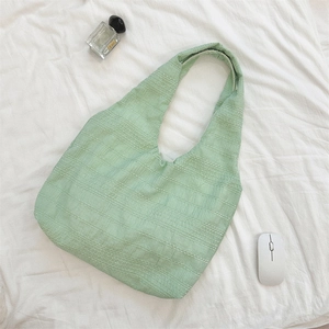 Detail of mint green tote bag featuring textured fabric and lightweight shoulder strap