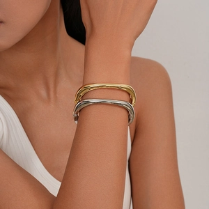 Dettaglio di bracciali rigidi impilati geometrici irregolari in oro e argento