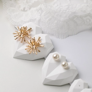Elegant gold sunflower earrings and pearl studs on heart shaped base with lace background