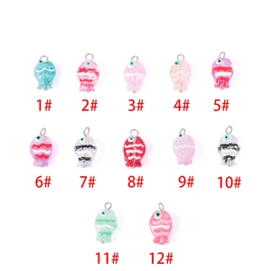 Detailed grid of twelve colorful handmade fish glass beads with silver metal rings for DIY