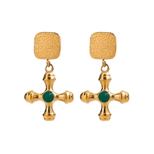 Gros plan sur des boucles d'oreilles vintage en or avec agate verte et croix en métal texturé