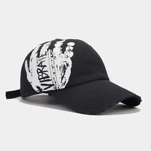 Detail view of distressed black baseball cap with white VIBRATE graffiti print