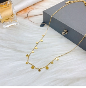 Detail of gold water drop titanium steel necklace on soft white plush background