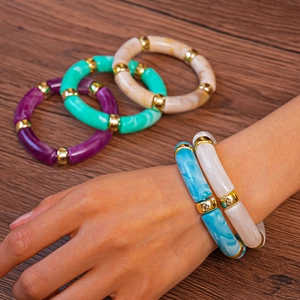 Détails de bracelets en résine acrylique avec perles dorées sur une surface en bois