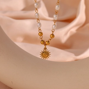 Detailed close-up of a golden sun face pendant with white freshwater pearls and gold beads