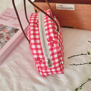 Detail of red gingham handbag featuring bow prints and durable brown leather cord handles