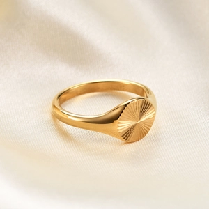 9mm gold stainless steel signet ring with radial sunburst pattern on silk background