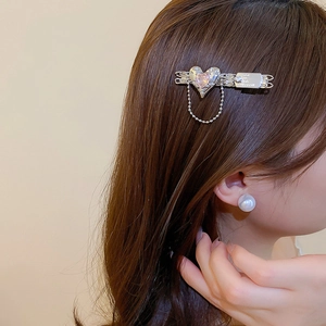 Detail of silver star hair clip with pink heart zircon and fine chain on brown hair