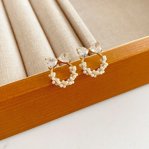 Vue macro de boucles d'oreilles nœuds en perles avec base or champagne et zircons
