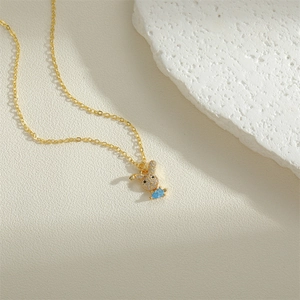 Golden rabbit pendant necklace with sparkling white zircons and a blue teardrop stone