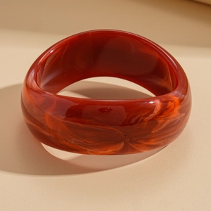 Detail of red-brown marble pattern resin bangle showing glossy wide geometric design