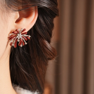 Gros plan de boucles d'oreilles fleurs bordeaux serties de zircon et émail brillant
