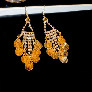 Detailed macro view of golden leaf tassel earrings with sparkling rhinestone accents