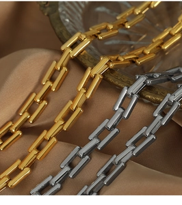 Detailed close-up of gold and silver rectangular link chains on luxury satin background