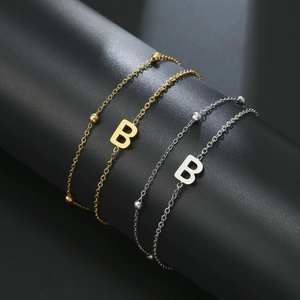 Detail of gold and silver plated bead bracelets with polished letter B charm