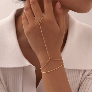 Detail of a minimalist 18K gold plated double layer hand chain and finger ring set