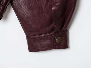 Detail of burgundy PU leather sleeve cuff with vintage metal snap button and stitching