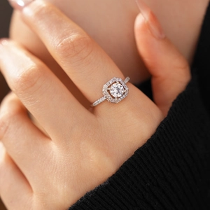 Detailed view of silver-tone halo ring with a round center stone on a model's hand