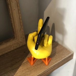 Funny duck resin statue with middle finger gesture holding a smartphone on a wooden shelf