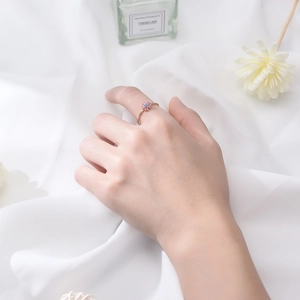 Detail of flower shaped gold ring with purple and blue gemstones on white silk background