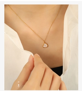 Gros plan d'un collier cœur avec nacre sur un mannequin portant une chemise blanche