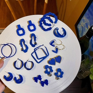 Detailed set of blue matte heart, butterfly, and hoop earrings in a white tray