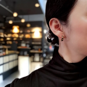 Close-up of stylish S925 silver hoop earrings with black and gold stripes on model