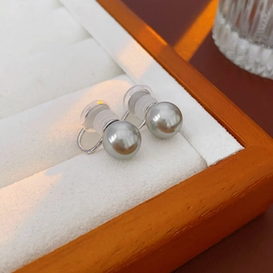 Detailed view of gray pearl ear clips with silicone pads on a premium jewelry display box