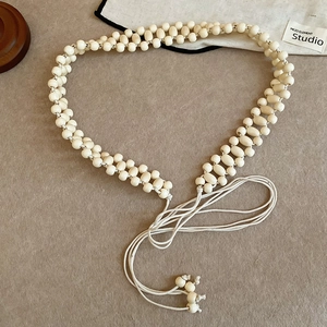 Close-up of handmade cream acrylic resin beads on bohemian woven waist chain belt